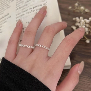 Close-up of minimalist silver hollow heart rings worn on fingers with a vintage book background