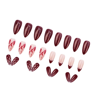 Short almond press-on nails in burgundy red with bow designs and white polka dots