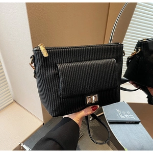 Detail view of black pleated texture bag with golden hardware and twist lock closure