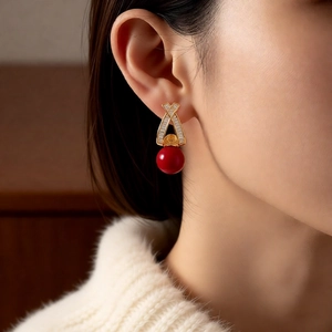 Macro shot of 18k gold earrings with baguette cubic zirconia and red pearl detail