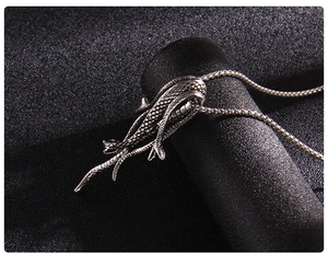 Détail du pendentif pieuvre argenté vintage avec textures d'écailles sur une chaîne serpent