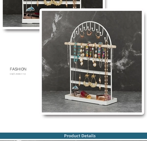 Detailed macro view of white 5-tier jewelry stand with wood rods and metal earring hooks
