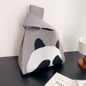 Detail of grey knitted tote bag with a panda pattern and unique triangular shape