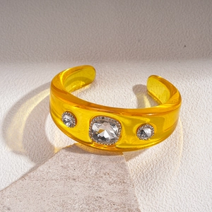 Detail of yellow resin open bangle with square center crystal and rhinestone accents