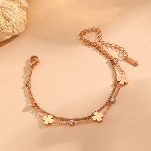 Détail macro du bracelet double couche en or rose avec trèfles et pierres de zircon