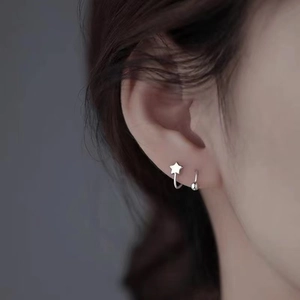 Detailed view of sterling silver star and bead stud earrings worn on the earlobe