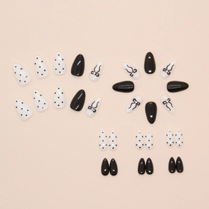Detailed set of black and white polka dot almond press-on nails with bow and pearl accents