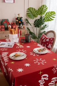 Close-up of festive red velvet Christmas tablecloth with snowflakes and Merry Christmas prints