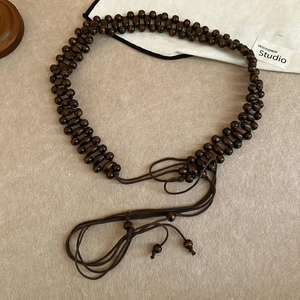Detail of bohemian dark brown wooden bead belt with intricate hand-woven double-row structure