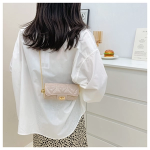 Quilted cylindrical crossbody bag in beige patent leather with golden chain strap on model
