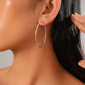 Silver geometric hoop earring displayed on a model's ear with high metal luster