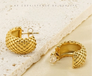 Macro detail of 18K gold plated C-shaped earrings with vintage dot texture on stone