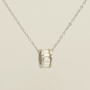 Macro view of silver cylindrical pendant with embedded clear crystal on steel chain