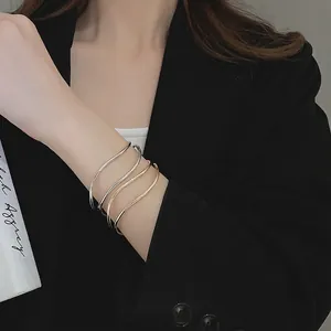 Minimalist wave bangle stack in gold and silver finish on a model's wrist