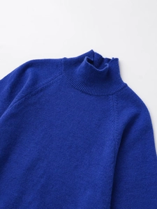 Détail macro du col montant bleu roi et de la maille à manches raglan du pull-over