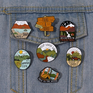 Detailed view of assorted enamel adventure badges on blue denim fabric background