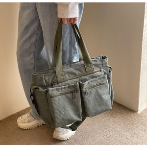 Detail view of large green corduroy tote bag with multiple pockets and adjustable strap