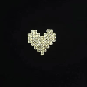 Detail macro view of heart-shaped pixel art brooch with white inlaid rhinestones