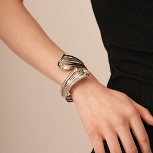 Detailed view of silver irregular geometric bangle with polished metallic finish on model