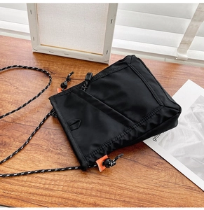 Detail of black nylon crossbody bag featuring adjustable black and white rope shoulder strap