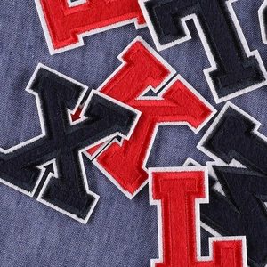 Red and black embroidered letter patches for clothes shown on blue denim background