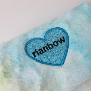 Detail of plush rainbow cosmetic bag with blue glitter heart and rainbow embroidery