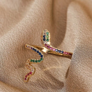 Détail de la bague serpent dorée avec zircons multicolores sur fond textile
