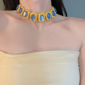 Close-up of vintage palace style choker with gold hollow patterns and blue oval gemstones