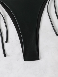 Macro view of matte black string bikini bottom featuring faux leather texture and straps