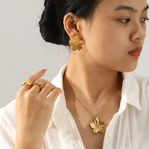 Gros plan d'une parure de bijoux fleur dorée avec collier et boucles d'oreilles sur mannequin