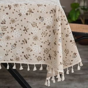 Detailed shot of beige cotton linen tablecloth with vintage floral pattern and tassel trim
