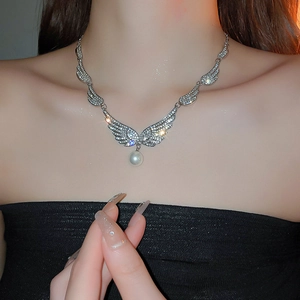 Detail of silver angel wing necklace with cubic zirconia and pearl on model