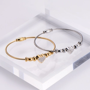 Gold and silver steel cable bracelets with micro-paved crystal heart charms and magnetic clasp