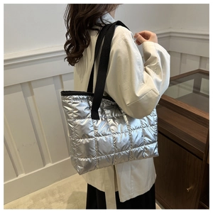 Silver quilted space cotton tote bag with black strap shown on model's shoulder