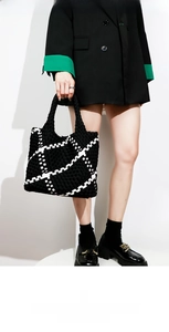 Detail of hand-woven tote bag showing black and white checkered pattern and sturdy handles