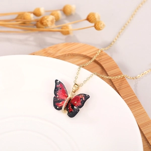 Detailed shot of red and black butterfly pendant necklace on a ceramic jewelry tray