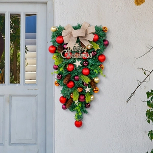 Christmas teardrop wreath with red and gold ornaments and burlap bow on white wall