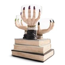 Detailed view of three spooky hand models emerging from antique books base as jewelry holder