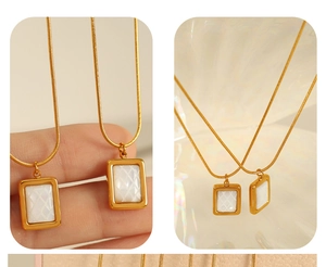 Détail d'un collier doré avec un pendentif rectangulaire en nacre blanche texturée