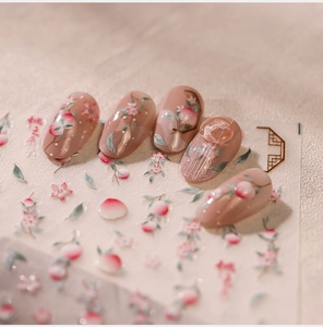 Macro shot of 3D peach nail art stickers featuring pink blossoms and gold frame details