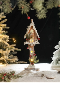 Detail of wooden Christmas house with LED lights, red berries, and faux snow decor