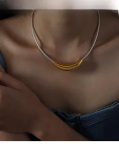 Close-up of minimalist gold curved pendant on silver snake chain worn by a model