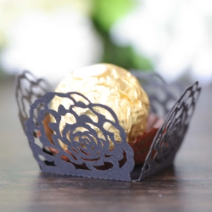 Close-up of laser-cut rose hollow favor box with chocolate on dark wood table