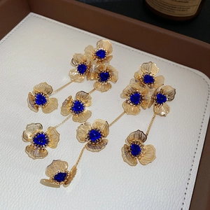 Detail view of triple-layered golden flower tassel earrings with blue gemstones