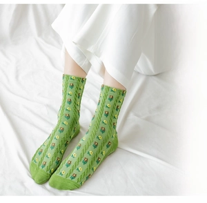 Detail of green mid-calf sock with yellow floral pattern and cable knit texture