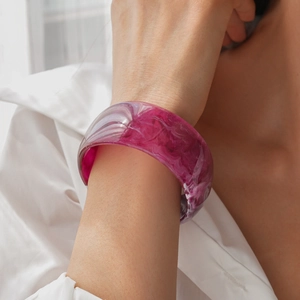 Macro shot of wide resin bangle featuring deep magenta marble texture on wrist