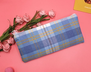 Detailed close-up of blue and yellow plaid canvas pencil case with a round zipper puller