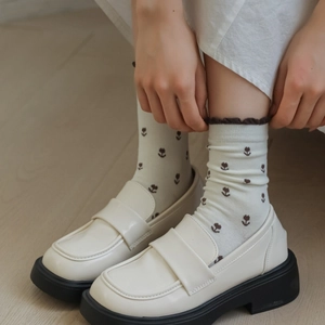Gros plan de mocassins en cuir crème avec semelle compensée noire et chaussettes à fleurs