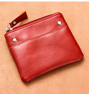 Detail of red pebbled leather wallet showing stitching, silver rivets and metal zipper