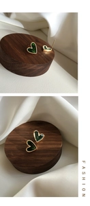 Detail view of vintage heart-shaped earrings in dark green enamel and gold plating
